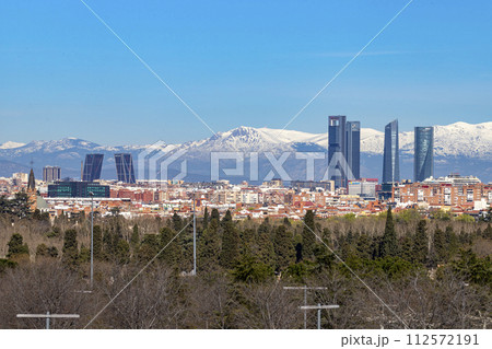 Sierra de Guadarrama. Mountain system seen from the city of Madrid with the recently snow-covered mountains covering the entire top of the mountain range in a white blanket. Skyline next to mountains. Sierra de Guadarrama. Mountain system seen from the city of Madrid with the recently snow-covered mountains covering the entire top of the mountain range in a white blanket. Skyline next to mountains. 112572191