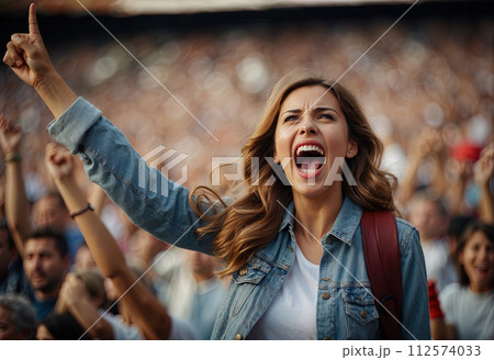 Female fan with raised arms shouting with among other fans in the stadium, stormy emotions. Generated AI 112574033