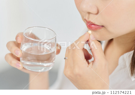 カプセル状の薬を飲む女性 112574221