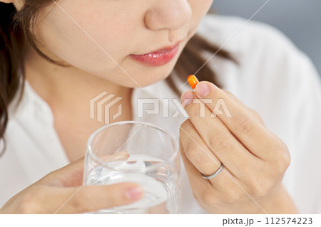 カプセル状の薬を飲む女性 112574223