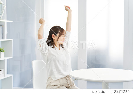 部屋で伸びをする女性 112574224