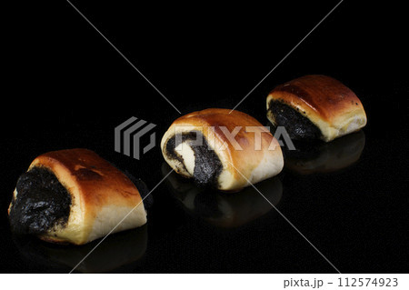 Buns with poppy seeds on a black background 112574923