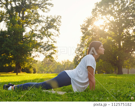 Young asian woman doing yoga in morning or evening at park, healthy woman relaxing in Upward Facing Dog Pose at city park. Mindfulness, destress, Healthy habits and balance concept Young asian woman doing yoga in morning or evening at park, healthy woman relaxing in Upward Facing Dog Pose at city park. Mindfulness, destress, Healthy habits and balance concept 112575182
