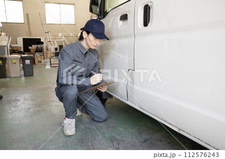 傷ついた車の修理の見積もりをする作業員 112576243
