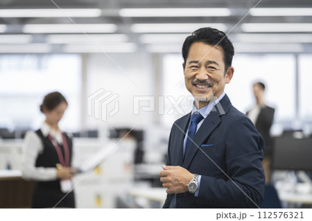 カメラ目線で笑顔の50代半ばのビジネスマン カメラ目線で笑顔の50代半ばのビジネスマン 112576321