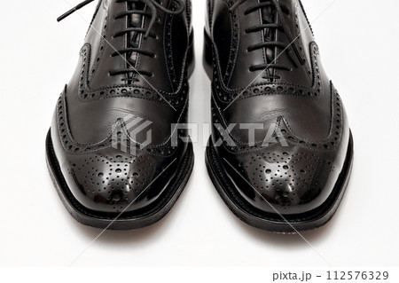 綺麗に磨いた黒いフルブローグの英国製革靴 112576329