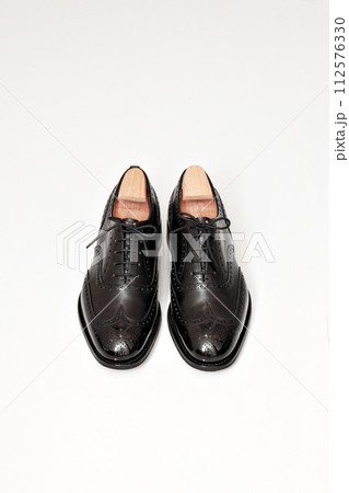 綺麗に磨いた黒いフルブローグの英国製革靴 112576330