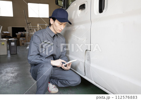 傷ついた車の修理の見積もりをする作業員 112576883