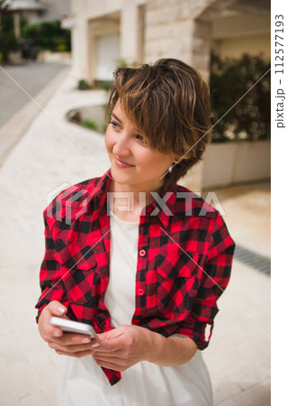 Young woman in a red shirt with smartphone on the city street. 112577193