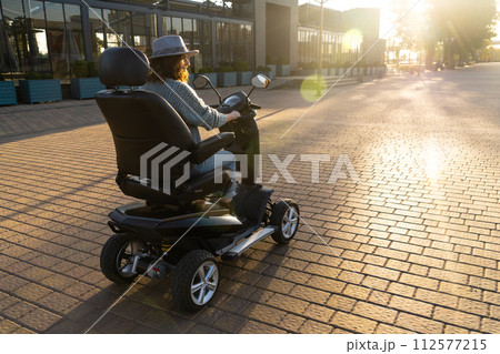 Woman tourist riding a four wheel mobility electric scooter on a city street 112577215