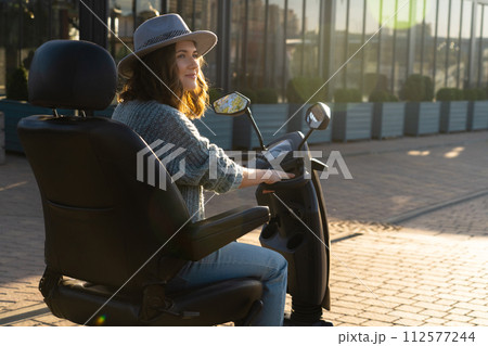 Woman tourist riding a four wheel mobility electric scooter on a city street 112577244