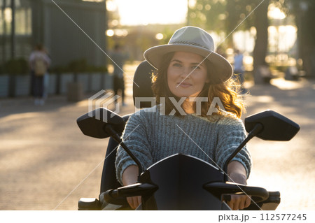 Woman tourist riding a four wheel mobility electric scooter on a city street 112577245