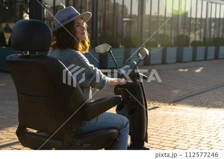 Woman tourist riding a four wheel mobility electric scooter on a city street 112577246
