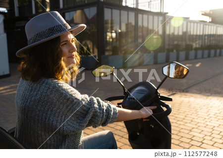 Woman tourist riding a four wheel mobility electric scooter on a city street 112577248
