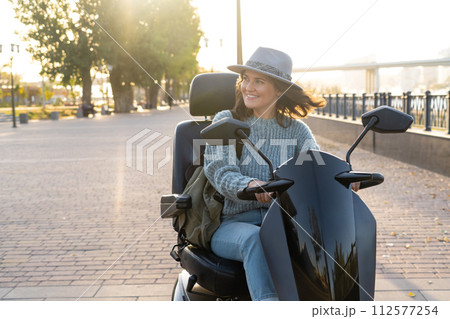 Woman tourist riding a four wheel mobility electric scooter on a city street 112577254