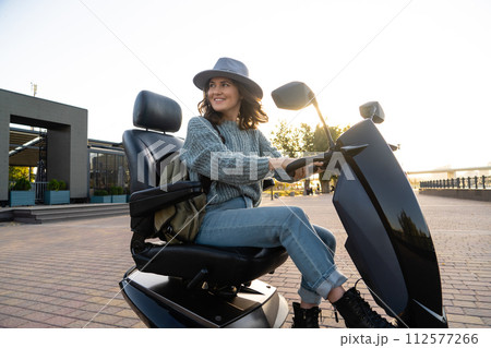 Woman tourist riding a four wheel mobility electric scooter on a city street 112577266