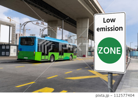 Road sign Low emission ZONE on a background of green electric buses. 112577404