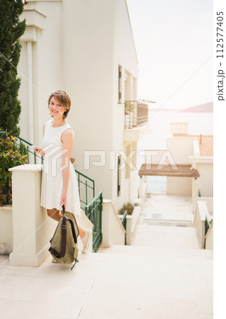 A woman holds a smartphone in her hands. Woman tourist on the street of coastal city 112577405