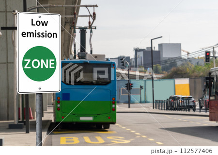 Road sign Low emission ZONE on a background of green electric buses. 112577406