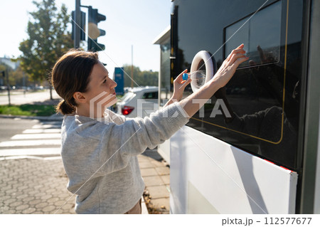 Woman uses a self service machine to receive used plastic bottles and cans on a city street.. 112577677