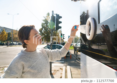 Woman uses a self service machine to receive used plastic bottles and cans on a city street.. 112577700