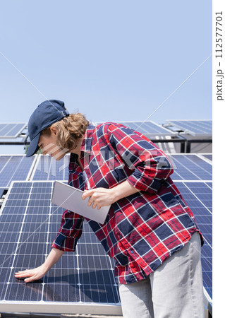 Woman with digital tablet touching solar panel. 112577701