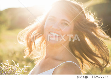 Smiling woman with flying hair at summer sunset. Smiling woman with flying hair at summer sunset. 112577727