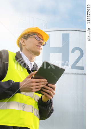 Engineer with tablet computer on a background of Hydrogen factory. 112577959