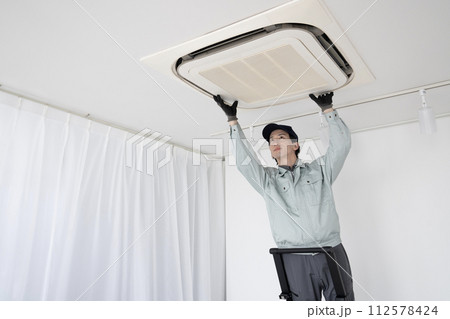 天上のエアコンの点検をする男性作業員 天上のエアコンの点検をする男性作業員 112578424