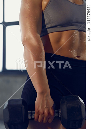 Cropped photo of young woman with muscular body in sportswear wet after productive weightlifting training at gym. Cropped photo of young woman with muscular body in sportswear wet after productive weightlifting training at gym. 112579424