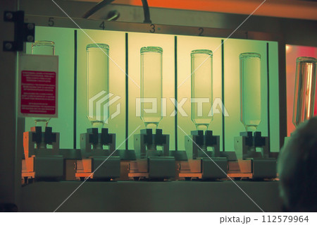 A distillery and winery pours the drink into glass bottles on conveyor lines. Industrial works, automated food and beverage production. A distillery and winery pours the drink into glass bottles on conveyor lines. Industrial works, automated food and beverage production. 112579964