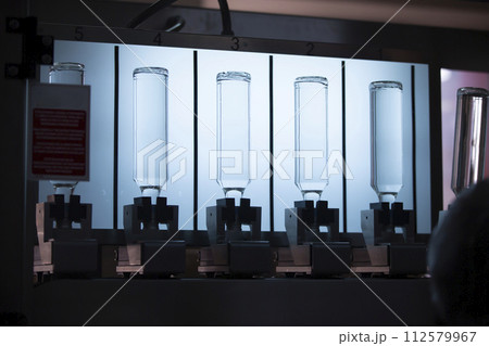 A distillery and winery pours the drink into glass bottles on conveyor lines. Industrial works, automated food and beverage production. A distillery and winery pours the drink into glass bottles on conveyor lines. Industrial works, automated food and beverage production. 112579967