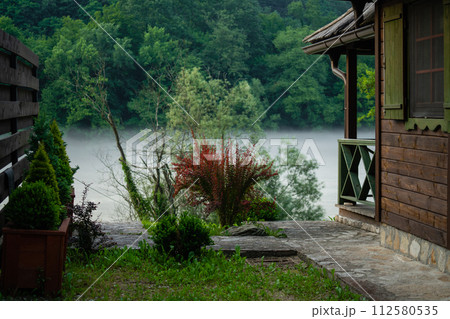 Porch of a wooden house in the forest on the river bank 112580535