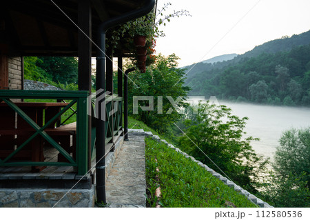 Porch of a wooden house in the forest on the river bank Porch of a wooden house in the forest on the river bank 112580536