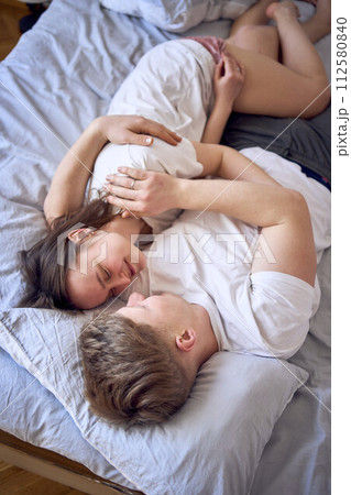 a young couple is lying on the bed, the girl is on the boy's shoulder, tender hugs a young couple is lying on the bed, the girl is on the boy's shoulder, tender hugs 112580840