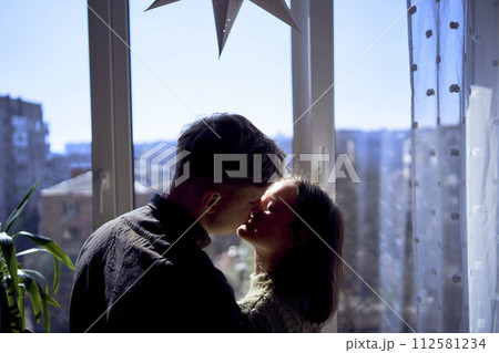 beautiful young couple kissing in the backlight against the window beautiful young couple kissing in the backlight against the window 112581234