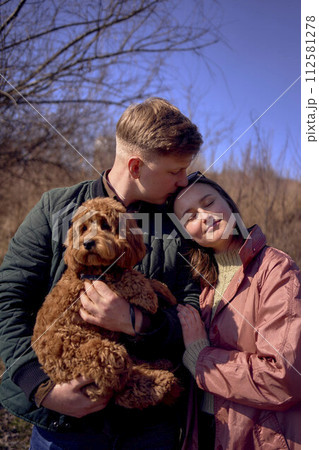 wife, husband and their cockapoo cuddle in the spring sun 112581278