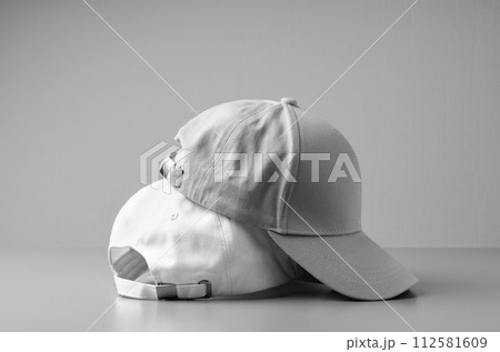 Two White Baseball Caps on a White Background 112581609