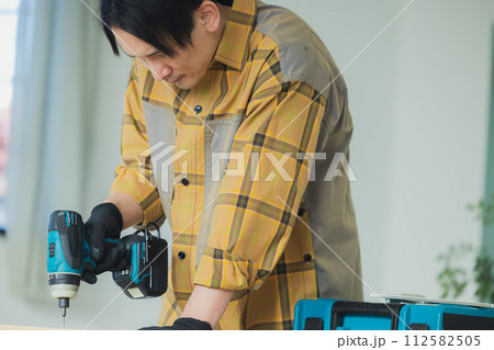 電動ドライバーで作業する若い男性 112582505