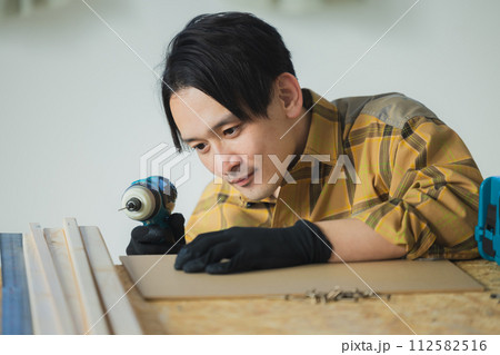 電動ドライバーで作業する若い男性 112582516