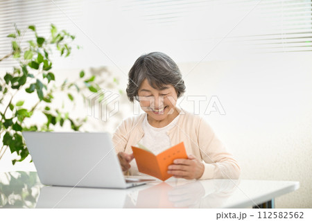 年金手帳を見ながらパソコンを使うシニア女性　終活 112582562