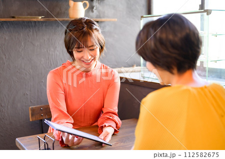 カフェでメニューを選ぶ二人の女性　 112582675
