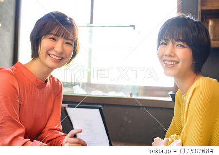 カフェでメニューを選ぶ二人の女性　 112582684