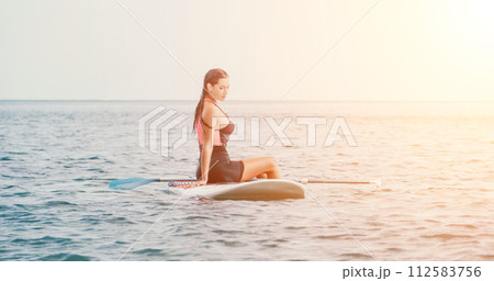 Sea woman sup. Silhouette of happy young woman in pink bikini, surfing on SUP board, confident paddling through water surface. Idyllic sunset. Active lifestyle at sea or river. Sea woman sup. Silhouette of happy young woman in pink bikini, surfing on SUP board, confident paddling through water surface. Idyllic sunset. Active lifestyle at sea or river. 112583756