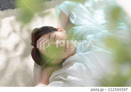 日差しを浴びて昼寝する女性 日差しを浴びて昼寝する女性 112584397