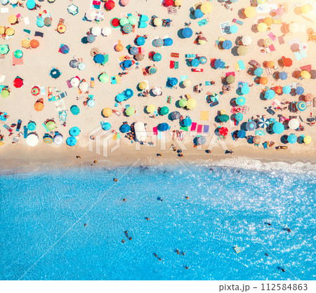 Aerial view of umbrellas on white sandy beach, blue sea at sunset Aerial view of umbrellas on white sandy beach, blue sea at sunset 112584863