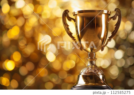 Shiny sparkling champion gold cup on golden bright background with sparkles , first place Trophy cup 112585275