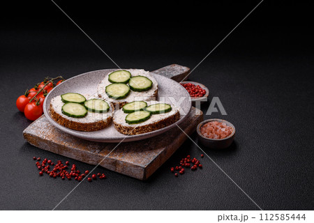 Delicious vegetarian sandwich with grilled toast, cream cheese, cucumbers and seeds 112585444
