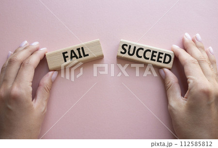 Fail or Succeed symbol. Concept word Fail or Succeed on wooden blocks. Businessman hand. Beautiful pink background. Business and Fail or Succeed concept. Copy space Fail or Succeed symbol. Concept word Fail or Succeed on wooden blocks. Businessman hand. Beautiful pink background. Business and Fail or Succeed concept. Copy space 112585812