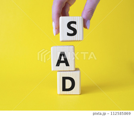 Sad symbol. Wooden cubes with words Sad. Businessman hand. Beautiful yellow background. Business and Sad concept. Copy space. 112585869